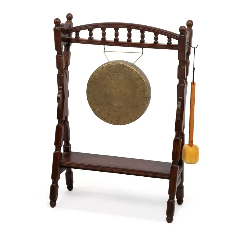 A Dinner Gong On An Oak Stand late 19th Century, the circular brass gong with a turned over rim and a hammered face