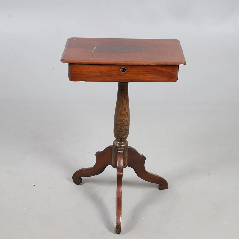 A mahogany topped occasional table, with a single drawer, raised on a turned oak column with three out swept mahogany supports