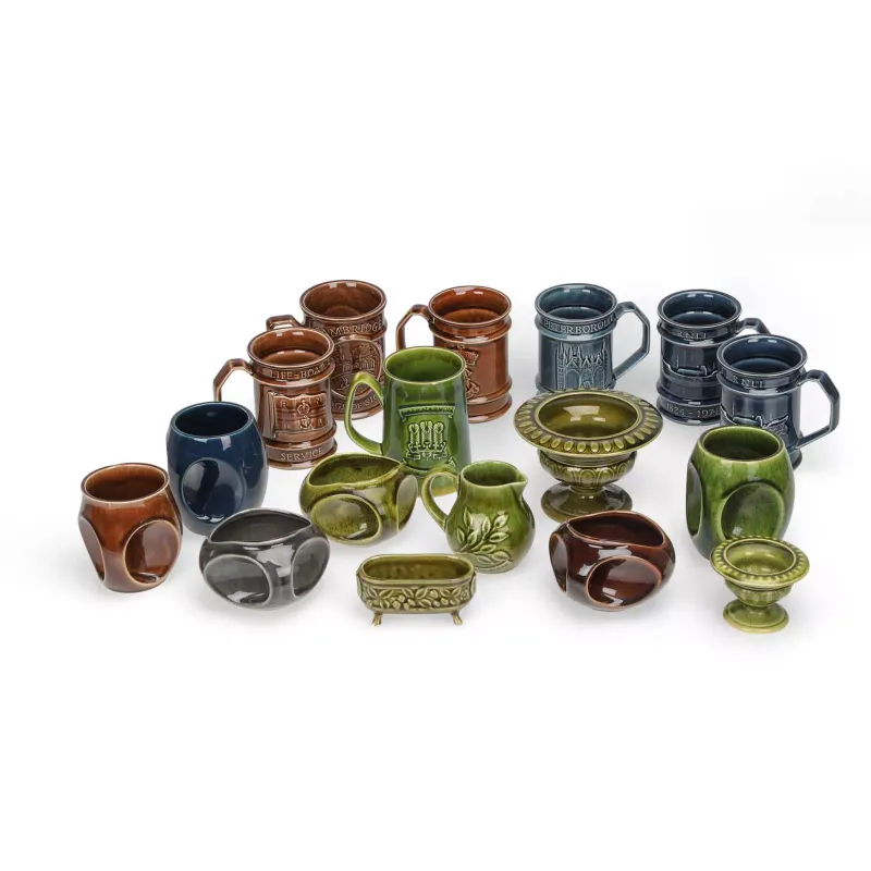 A Collection Of Holkham Pottery in treacle, green, blue and grey glazes, including tankards moulded with the Holkham estate arms, cube-form candle holders