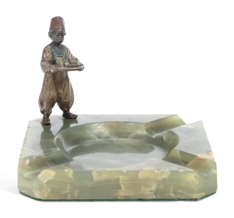 An Austrian Cold Painted Bronze And Onyx Ashtray Early 20th Century mounted to one corner with a figure of an Arab boy in a fez and waistcoat carrying a tray of
