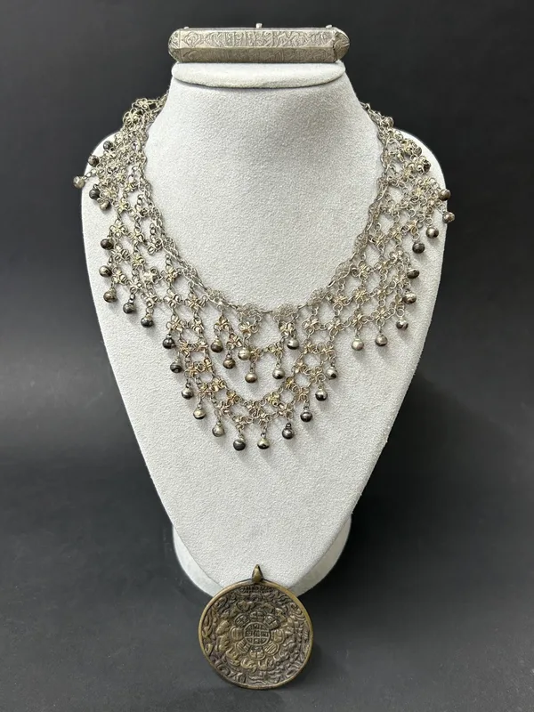 A vintage white metal prayer necklace together with a white metal ball necklace and a Tibetan brass calendar