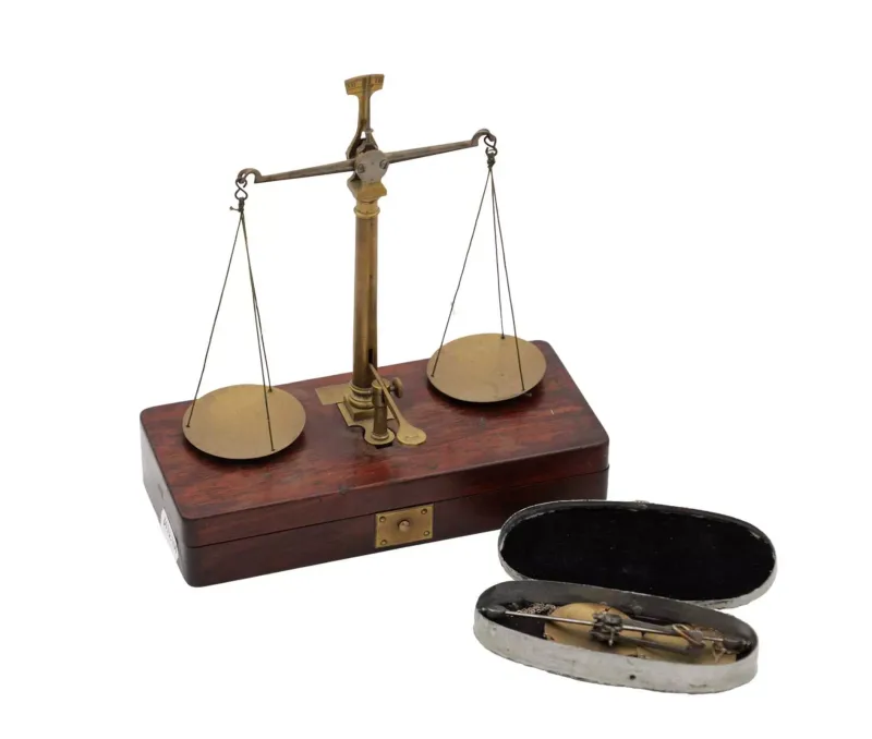 Two Cased Brass Balance Scales comprising a Georgian jeweller's balance mounted on a fitted mahogany case with twin pans and central column together with a pock