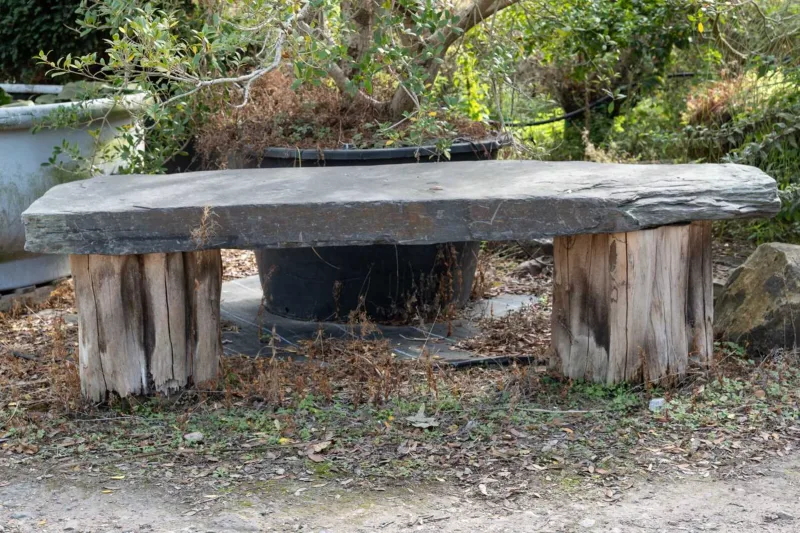 A large garden bench The bench constructed from a large piece of slate on two logs The slate top