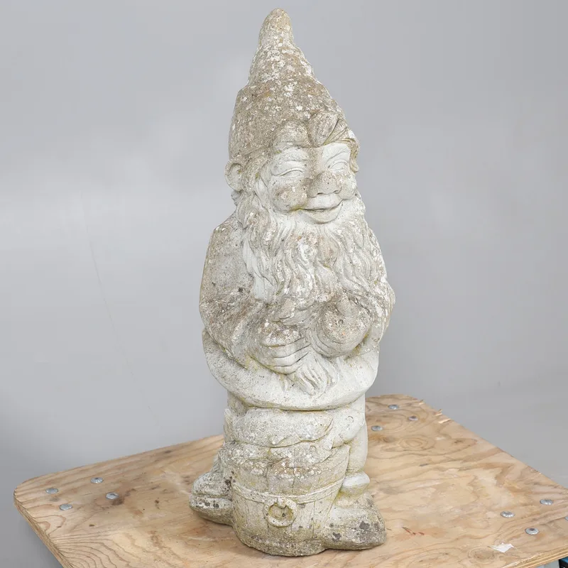 A stone garden gnome statue, depicted with a barrel of fish between the feet,