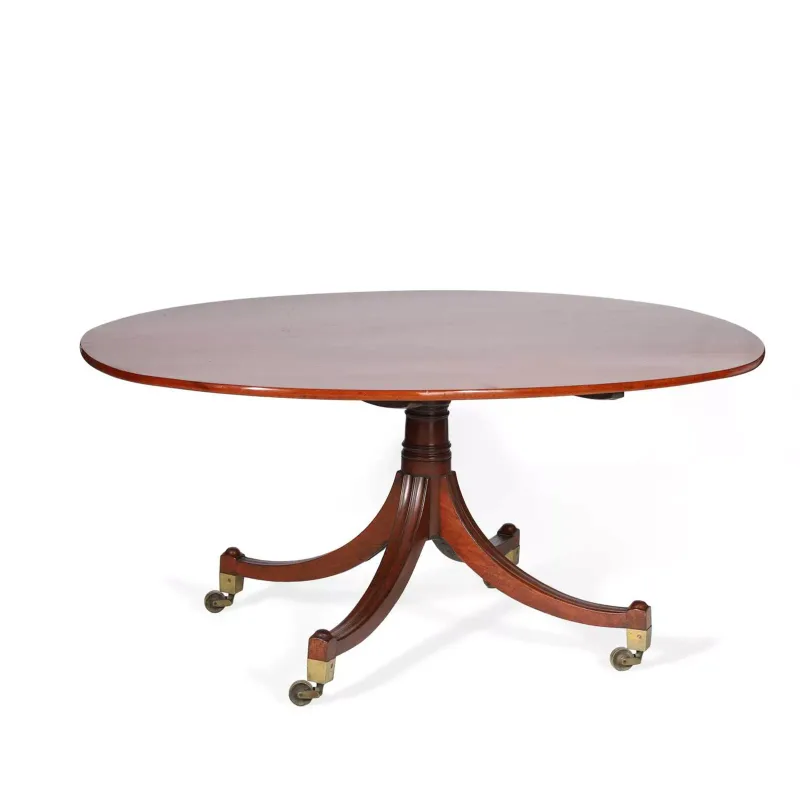 A Regency Mahogany Breakfast Table circa 1820, the oval tilt top upon a turned and reeded column with four downswept reeded legs