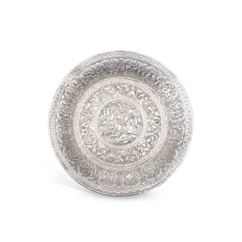 An Indian Silver Dish of circular form, repoussé decorated to the centre with a seated deity surrounded by animals within a landscape