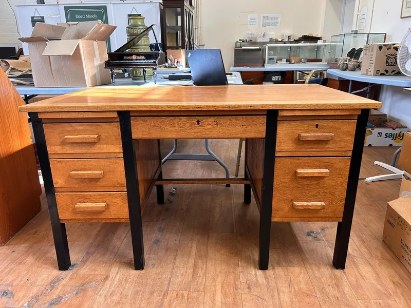 A 20th century pale stained wood and metal-framed kneehole desk fitted seven drawers,