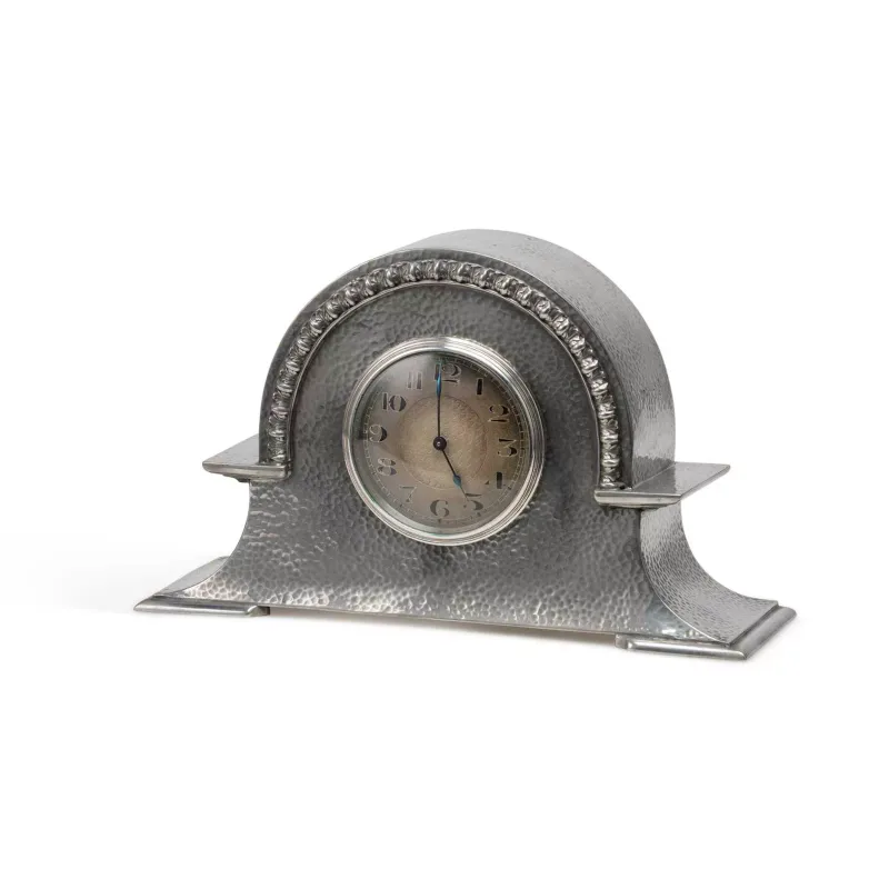 An Arts And Crafts Pewter Mantel Clock by Fenton Brothers, Sheffield, the arch-topped case with hammered decoration, cast with a repeating vine leaf motif