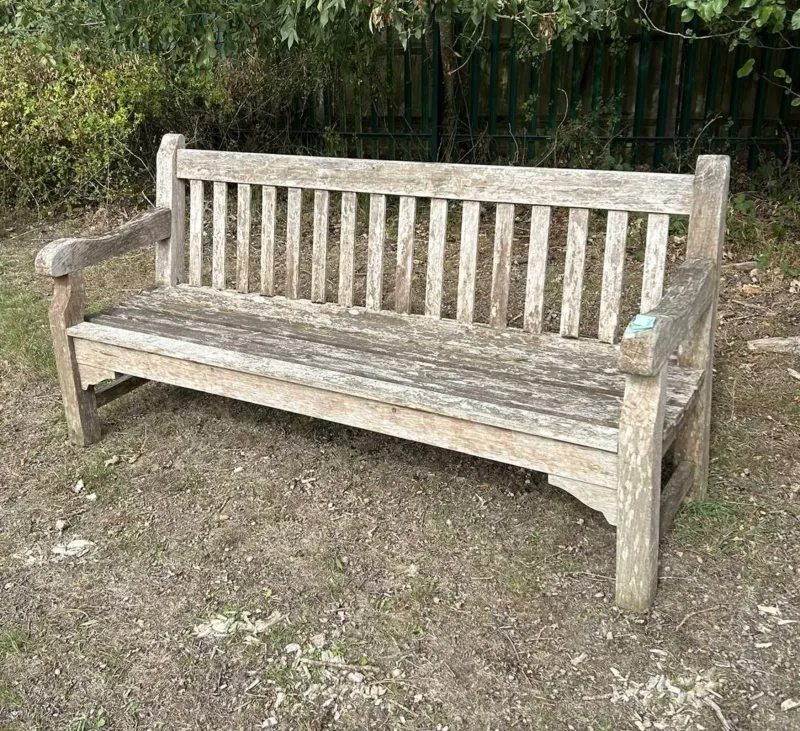 A teak garden bench by Barlow Tyrie The bench with slatted backs and seats and shaped arms, all on square legs