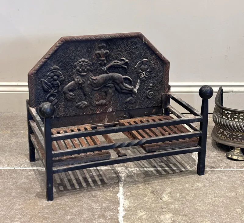 A 19th century cast iron fire back, depicting a lion amidst a Tudor rose and thistle, with conforming grate,