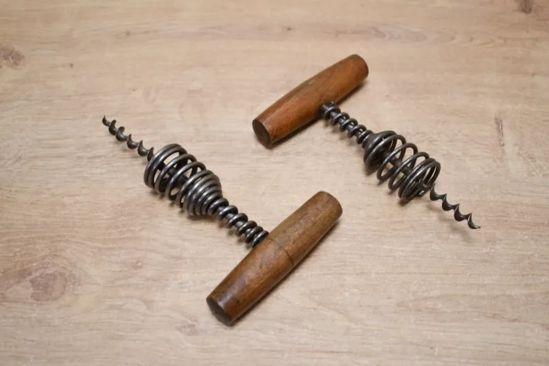 Two early 20th-century spring barrel corkscrews, having a wooden T-handle and a helical spring, unmarked, (2),