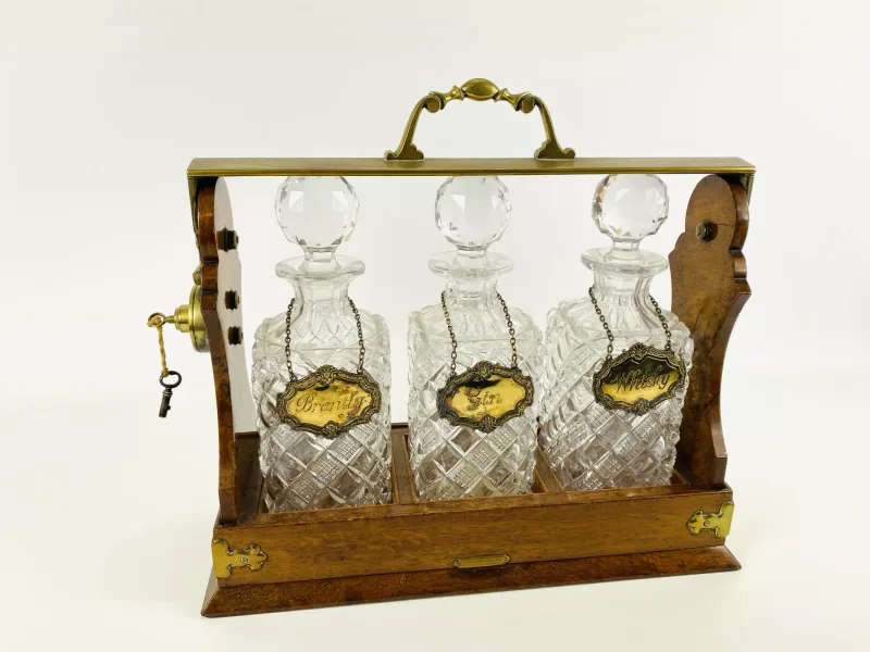 A Victorian pollard oak three decanter tantalus with brass mounts and fittings, the decanters with hallmarked silver labels (Brandy, Gin and Whisky)