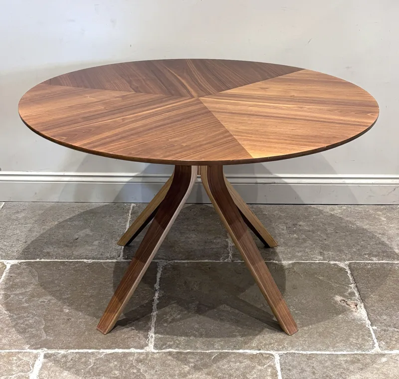A 'Radar' circular dining table by Wales And Wales for John Lewis, the bent wood geometric legs supporting a six seat veneered table top,