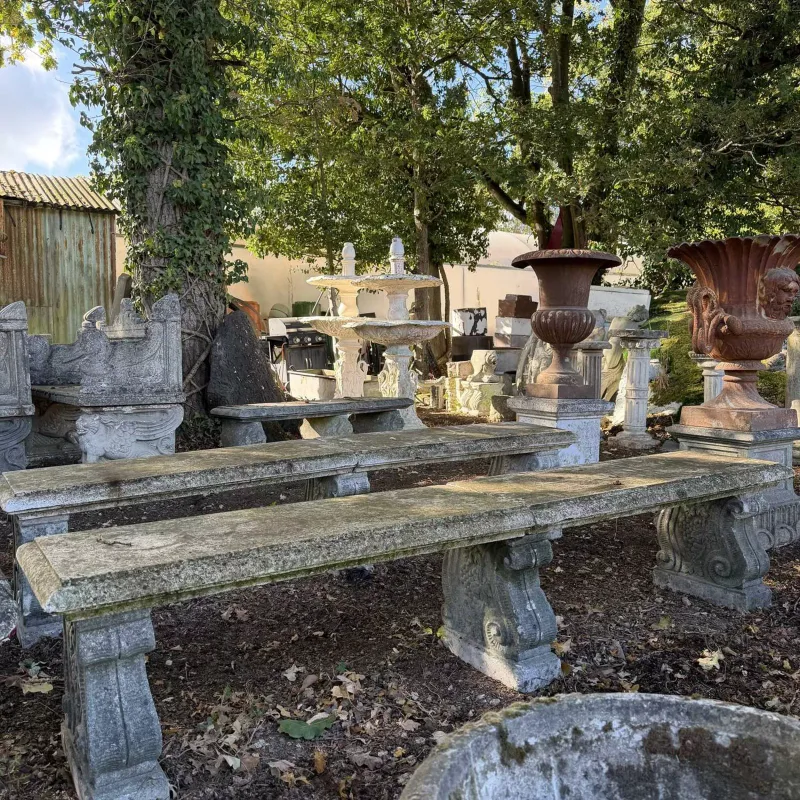 A pair of long garden benches The two cast reconstituted stone benches each with scroll and fruiting vine supports