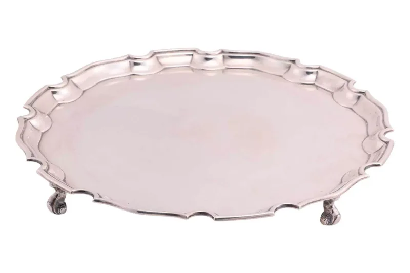 A silver salver by J Vander Ltd, London 1958, with pie crust border on four scroll feet,