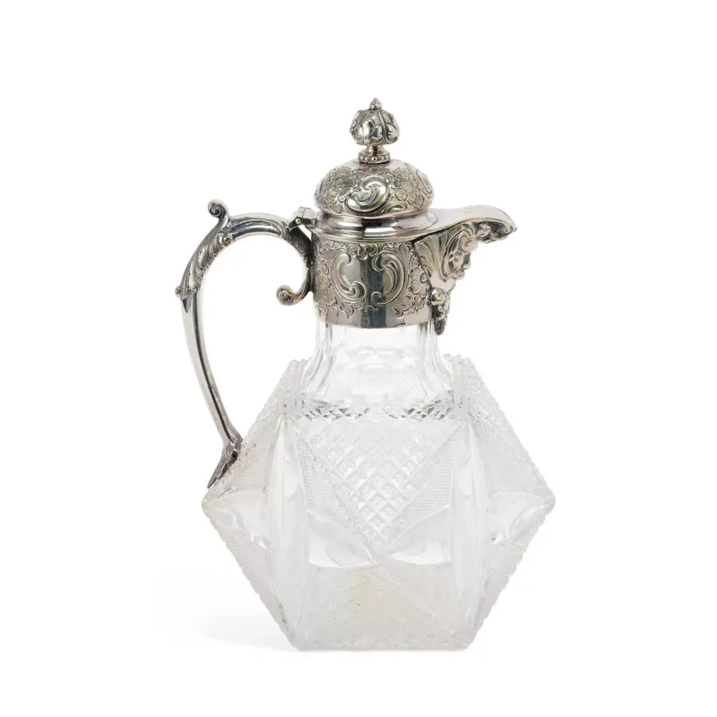 A Victorian Silver-Plated And Cut-Glass Claret Jug of dodecahedron type form with diamond-cut panels, the silver-plated domed cover embossed with scrolls