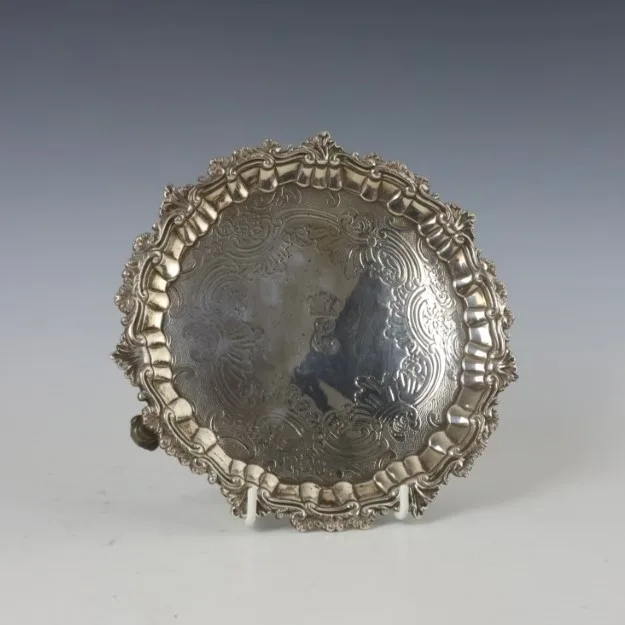A George III silver salver, Robert Garrard I, London 1815, the shell cast rim above later engraved well, upon three scroll feet,