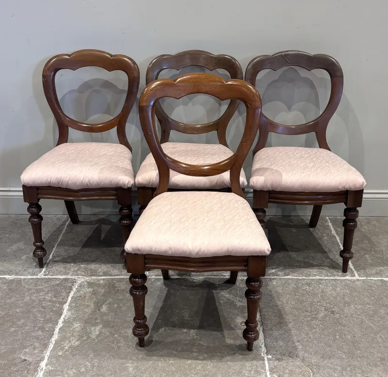 A set of four Victorian mahogany balloon back dining chairs, each with drop-in seat pads, and raised on turned four legs and rear sabre legs