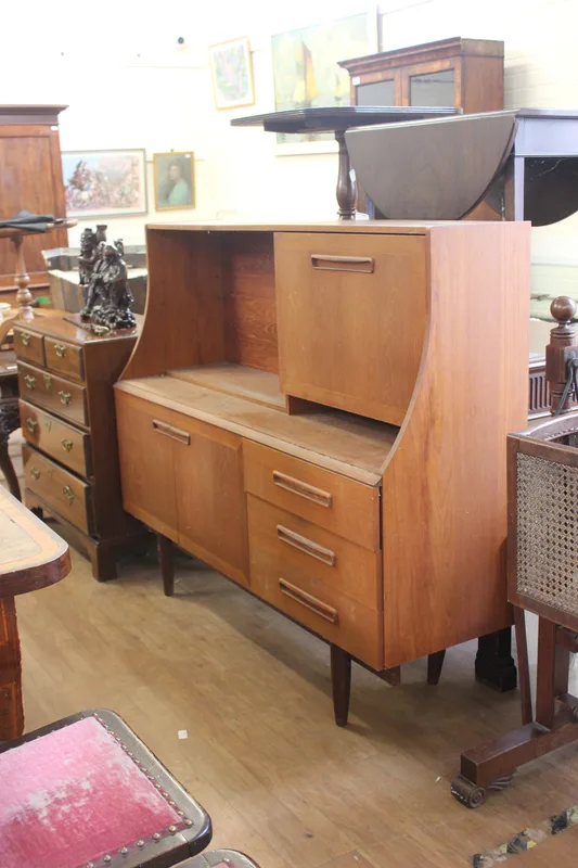 A mid-century teak Danish-style sideboard fitted doors and cupboards, a fall front, and a single shelf,
