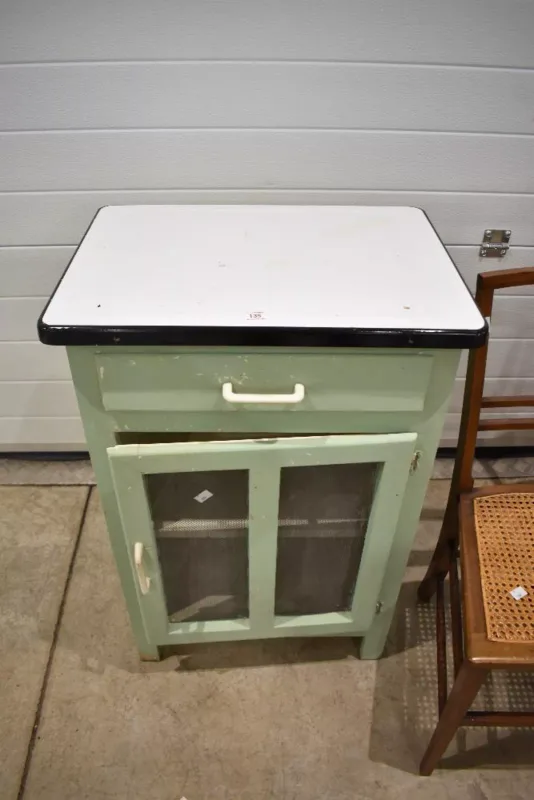 A mid-20th-century painted wood kitchen cabinet, the exterior finished in a pastel green with a cream-painted interior