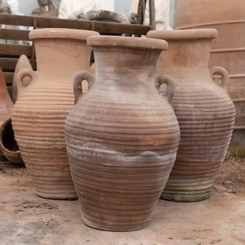 A group of three North African storage jars The terracotta jars of baluster form with lug handles and ribbed decoration to the bodies The largest approximately