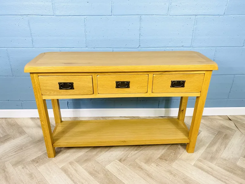 A good quality contemporary solid oak serving table with three frieze drawers over a pot board base below. 122cms wide x 35.5cms deep x 77cms high