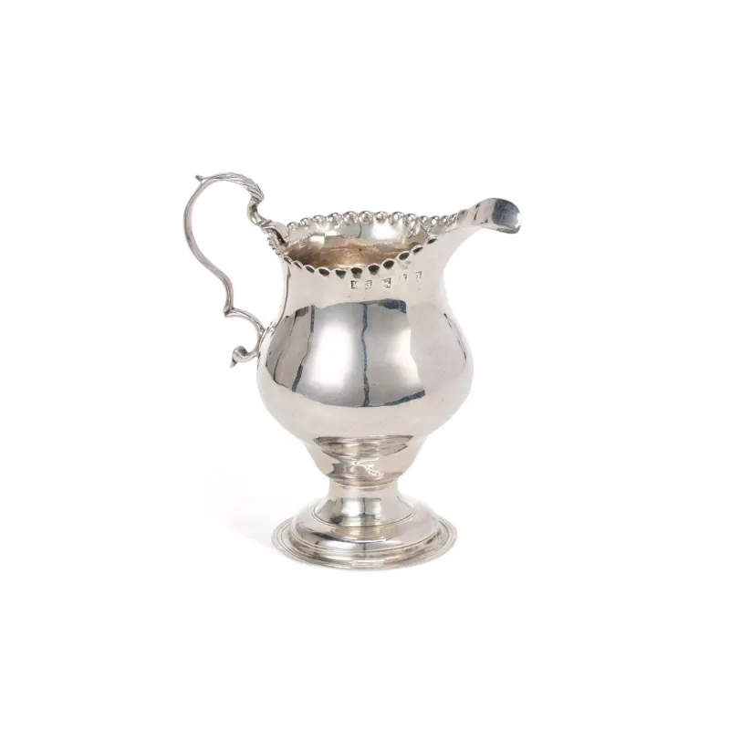 A Georgian Silver Cream Jug marks rubbed, of baluster form atop a multi-stepped circular pedestal with Btm engraved on the underside