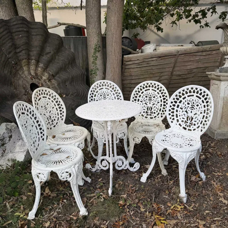 A cream painted garden table and chairs The table with pierced top and scrolling supports