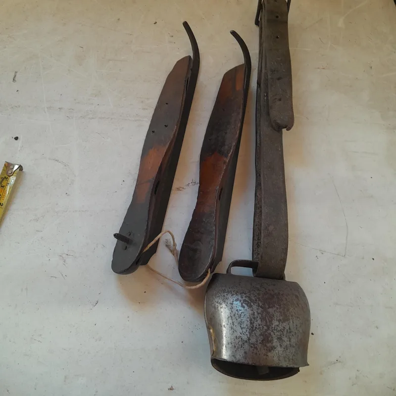 Pair of Victorian ice skates and vintage cow bell on leather strap