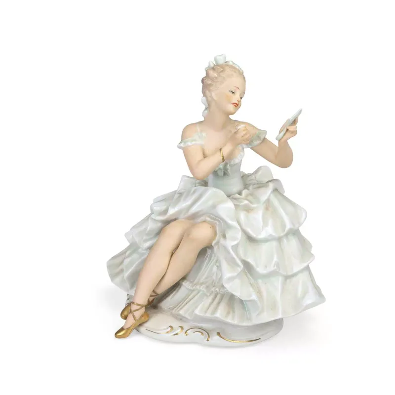 A Wallendorf Porcelain Figure Of A Seated Lady mid-20th Century, modelled seated in a flounced pale green crinoline, holding a hand mirror and powder puff