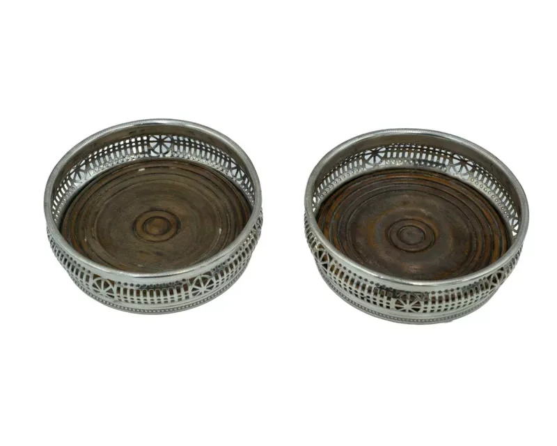 A pair of white metal bottle coasters