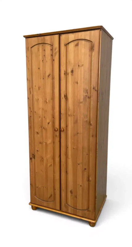 A contemporary pine wardrobe with arched panel doors enclosing a shelf and hanging section raised on bun feet