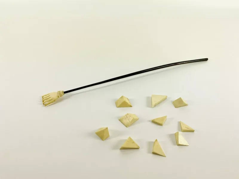 Two items to include a 19th century carved bone back scratcher in the form of a hand with a horn handle (37.5cms long), together with a bone puzzle block