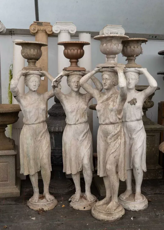 A group of four composite sculptures of caryatid females Each sculpture holding a small urn aloft