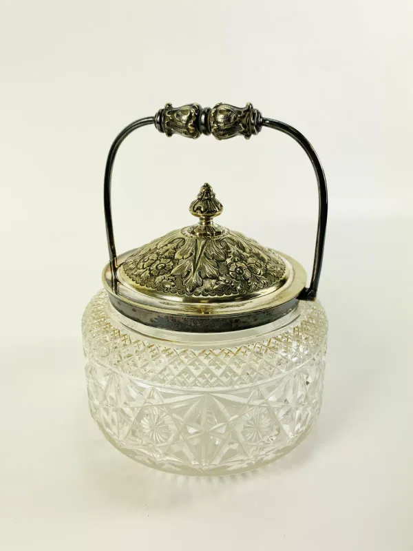 An attractive early 20th century silver plated biscuit barrel with an acanthus swing handle and a cut glass main body. 15cms wide x 15cms deep x 19.5cms high to