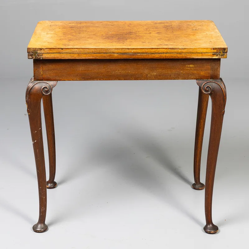 A 19th century fold over card table, burr veneer top raised upon a mahogany frame base, having cabriolle supports with scroll carved knees and pad feet