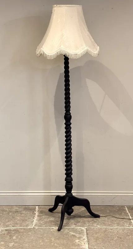 A late 19th century oak standard lamp, the barley twist column raised on a tripod base with outswept supports, with shade