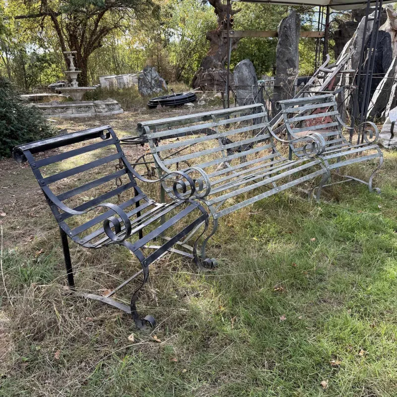 A suite of garden furniture The wrought iron bench and two matching chairs each with scrolling arms