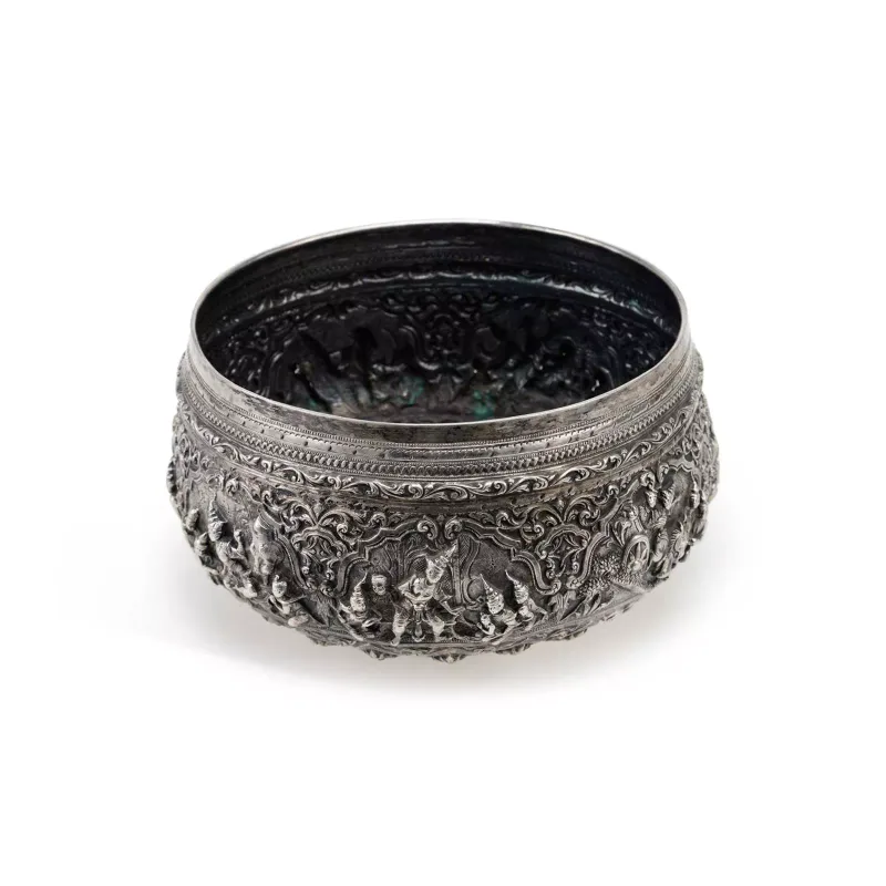 A Burmese Silver Offering Bowl late 19th/ early 20th Century, decorated in relief with figural panels amongst scroll and foliate borders.