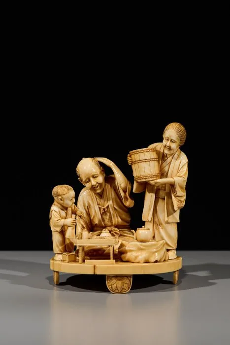 A finely carved ivory okimono of a family scene - Meiji period (late 19th century)