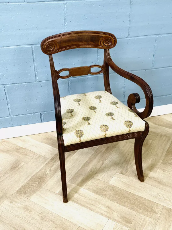 A good early 19th century Regency mahogany elbow chair with scrolling arms and carved decoration
