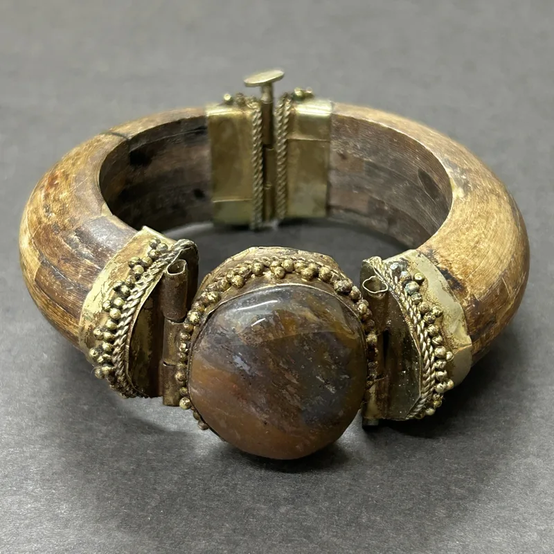 A vintage wood and metal cuff bracelet set with a large stone