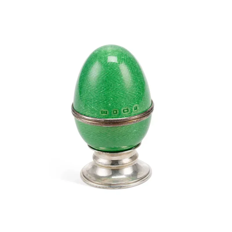 An Elizabeth II Silver And Enamel Egg On Stand marked Mc, Sheffield 1998, in green guilloché enamel, opening at the centre to reveal a fabric-lined interior