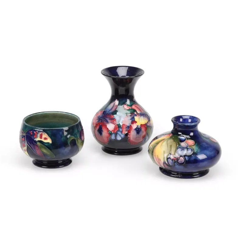 A Moorcroft 'Pansy' Vase, A 'Leaf And Berry' Vase And An 'Orchid' Bowl comprising the Pansy vase of baluster form with a flared neck