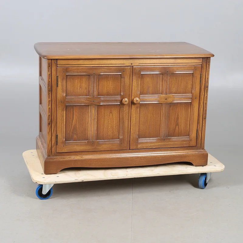 An Ercol old colonial stereo unit cupboard, comprising of two panelled cupboard doors surrounded by a carved border