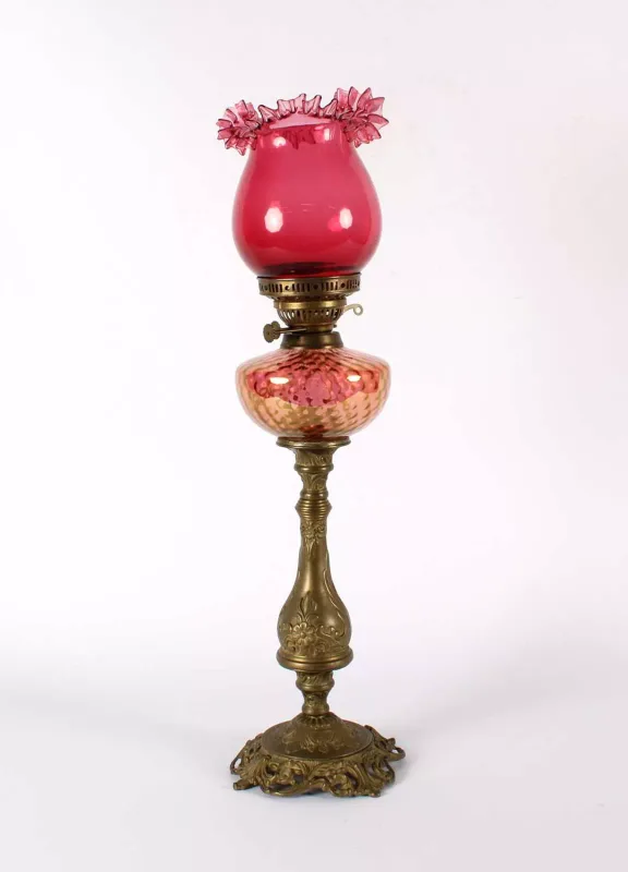 A Late 19th/Early 20th Century Art Nouveau Brass Oil Lamp A Late 19th/Early 20th Century Art Nouveau Brass Oil Lamp , with cranberry glass shade