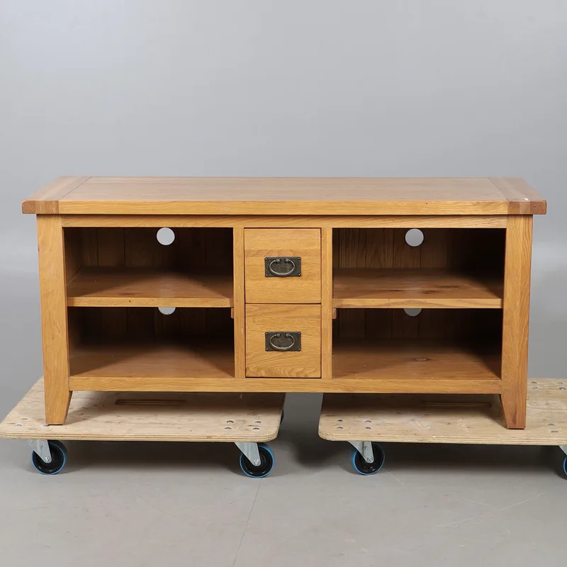 An oak low television stand with central drawers, with two short central drawers, with two open shelves, raised on supports.