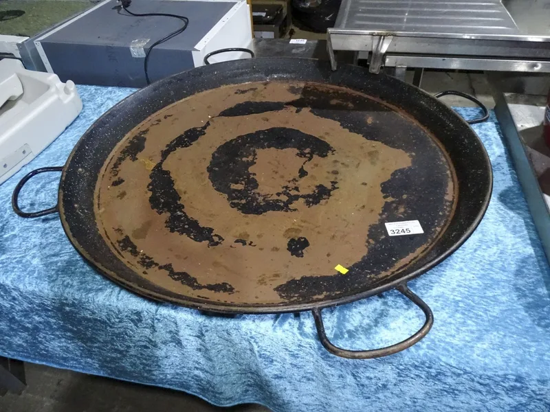 A large round metal Paella pan with 4 handles