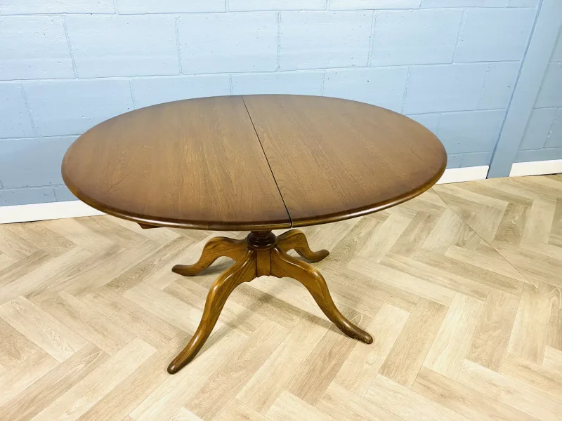 An extending Ercol table with a concealed foldaway leaf, with a turned central column and raised upon four shaped legs