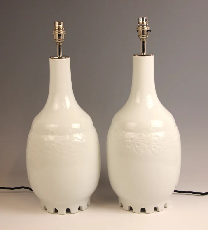A pair of Chinese influence contemporary white glazed table lamps by Keramis, each of shouldered baluster form with relief moulded foliate detail